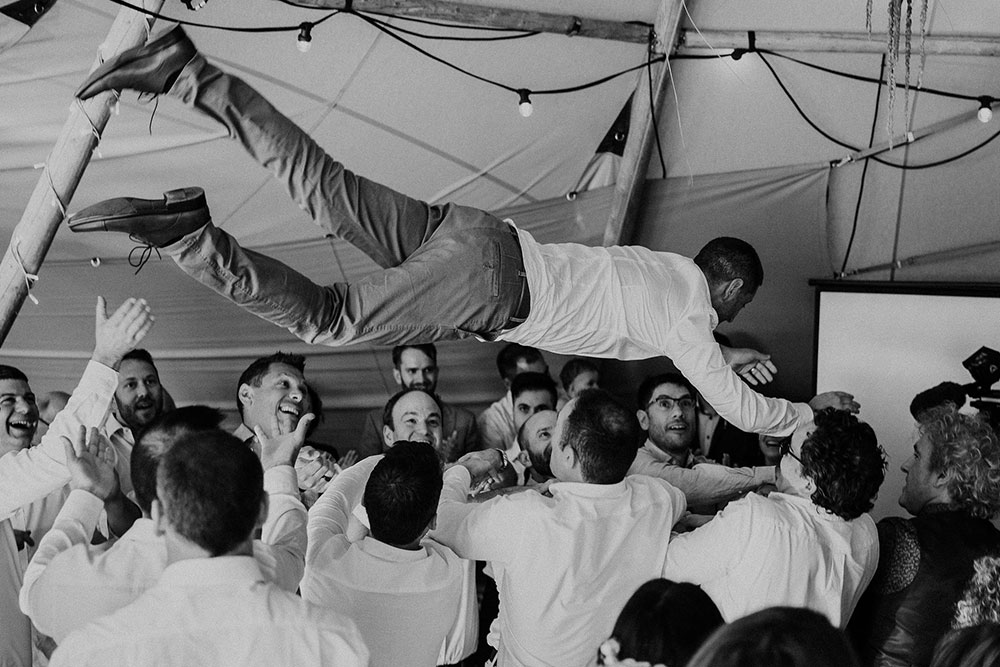Tipi wedding by Gather and Gold - double tipi set up, joined to provide cover, one area for dining, one for dancing. Groom being carried overhead by guests