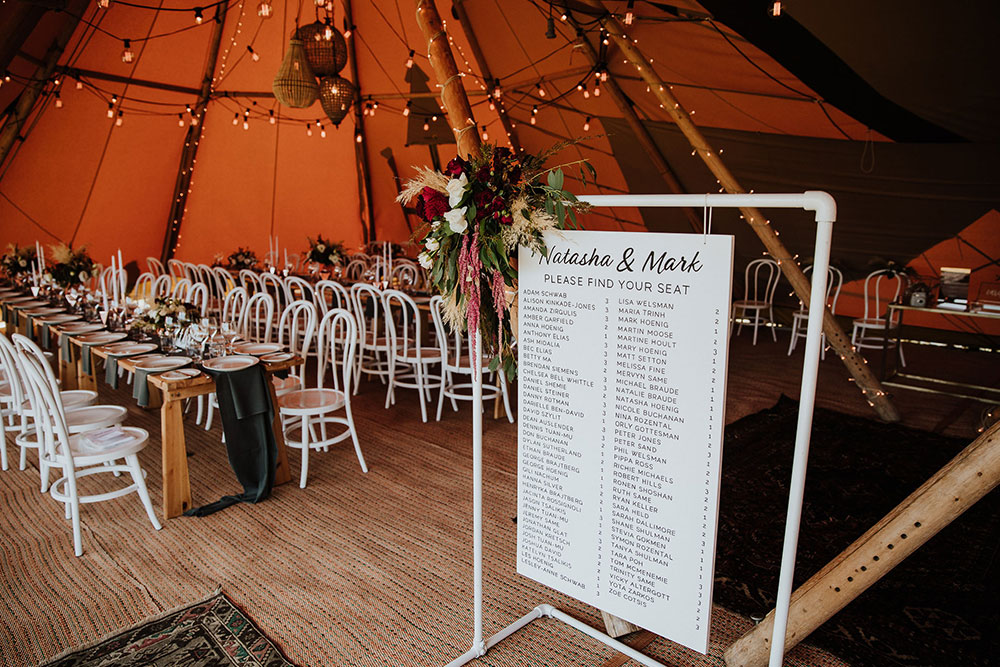 Tipi wedding by Gather and Gold - double tipi set up, joined to provide cover, one area for dining, one for dancing. Dining area with long tables and guest seat sign