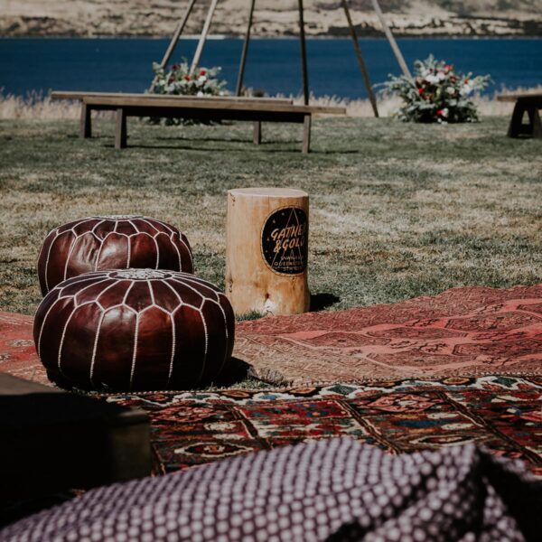 Gather and Gold tipi hire wedding - rustic rug and cushion seating outside an event in Queenstown with tipi frame and lake behind