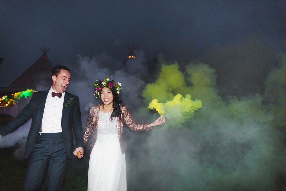 Bride and Groom with colourful chalk in the air at their festival tipi wedding in New Zealand