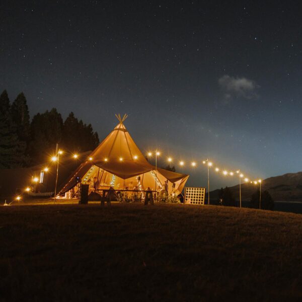 Gather and Gold large teepee tent hire - view of teepee at night with glowing festoon lights