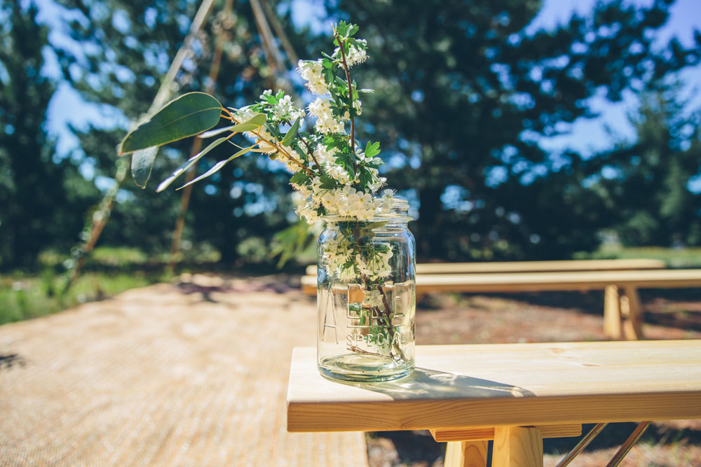 Glass jar with flowers in front of naked mini tipi arbor - tipi wooden frame without covering for wedding by Gather and Gold