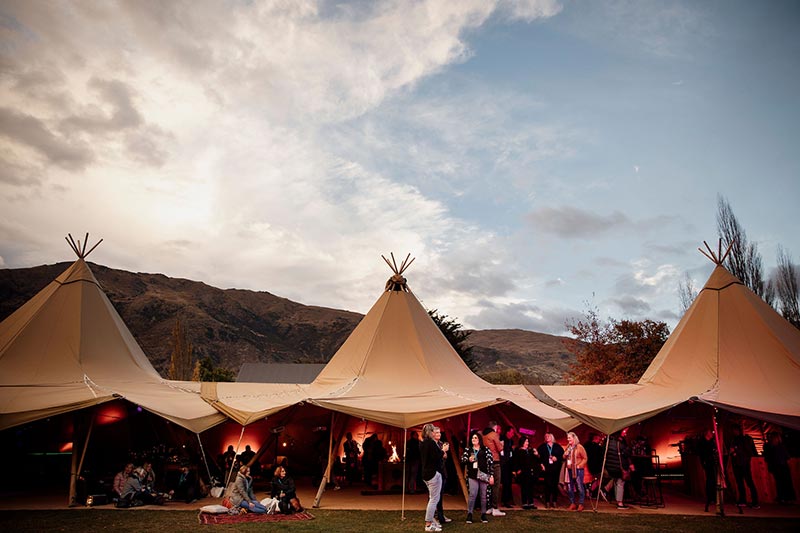 Three Gather and Gold tipis at dusk at a corporate event