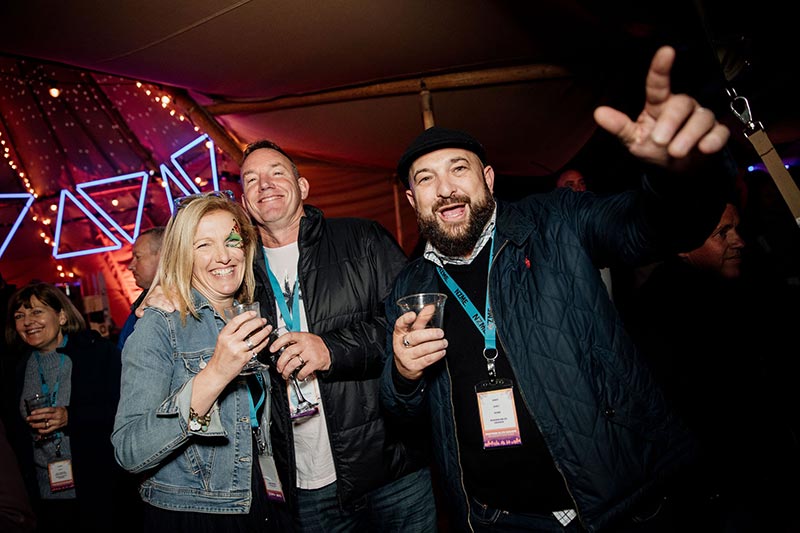 Group of people smiling and laughing at a corporate event in a Gather and Gold tipi.