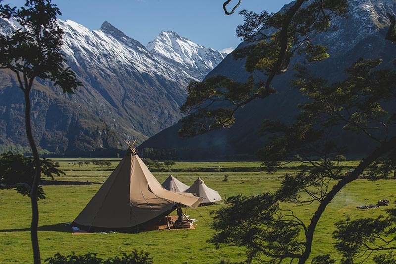 Gather and Gold tipi in an field surrounded by snow capped mountains in the South Island of New Zealand.