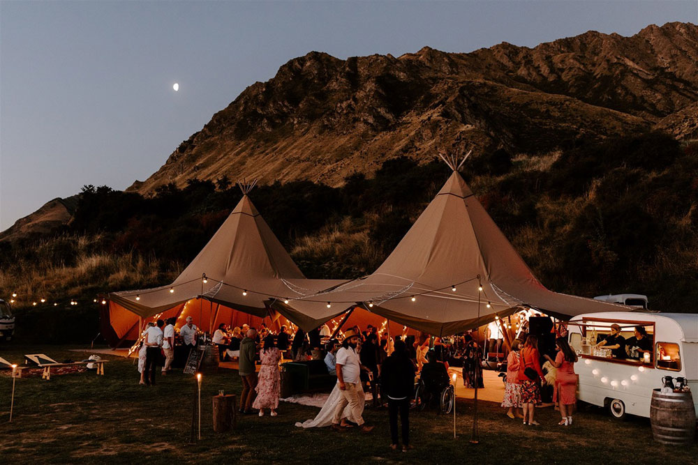 two tipis lit up at dusk in the mountains