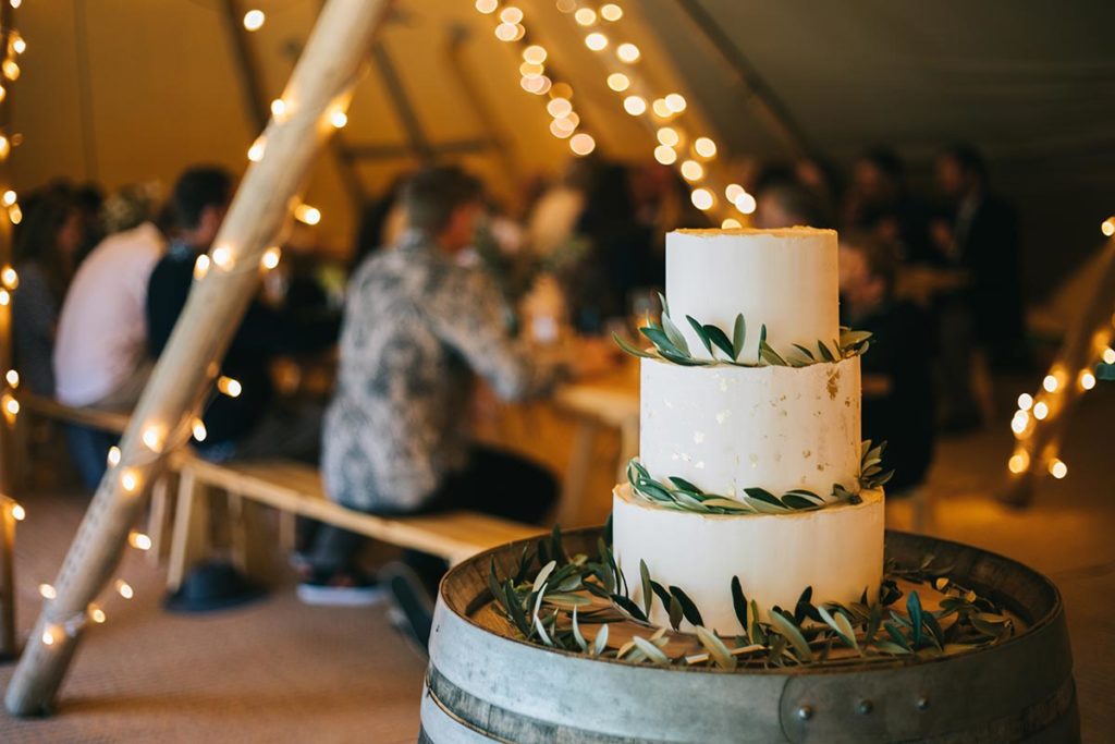 Gather and Gold Teepees recommends Flower, caterers and wedding planners in Queenstown and Wanaka - tiered wedding cake on a barrel in a tipi.