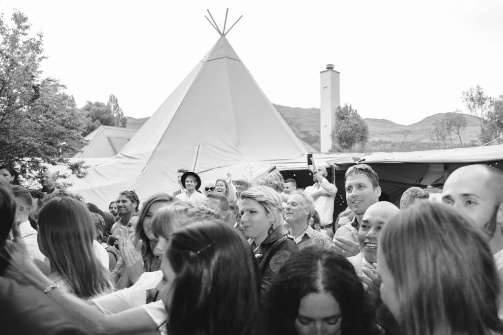 A group of people party in front of a tipi