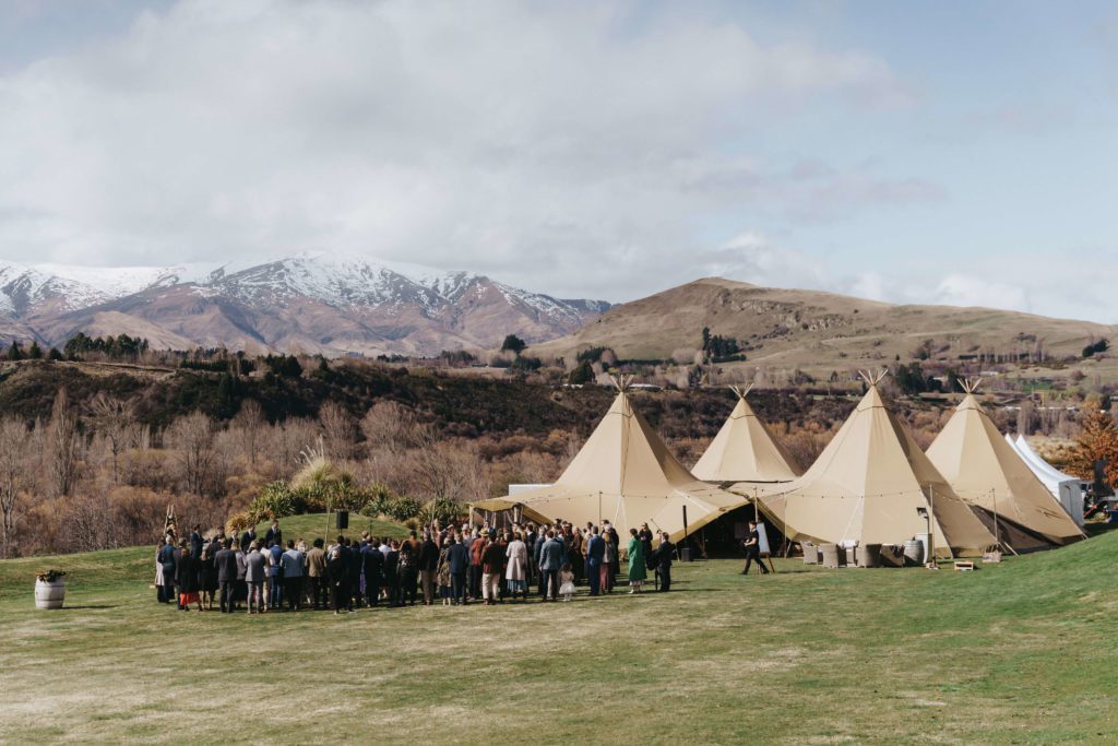 Tipis behind mountains with wedding guests in front