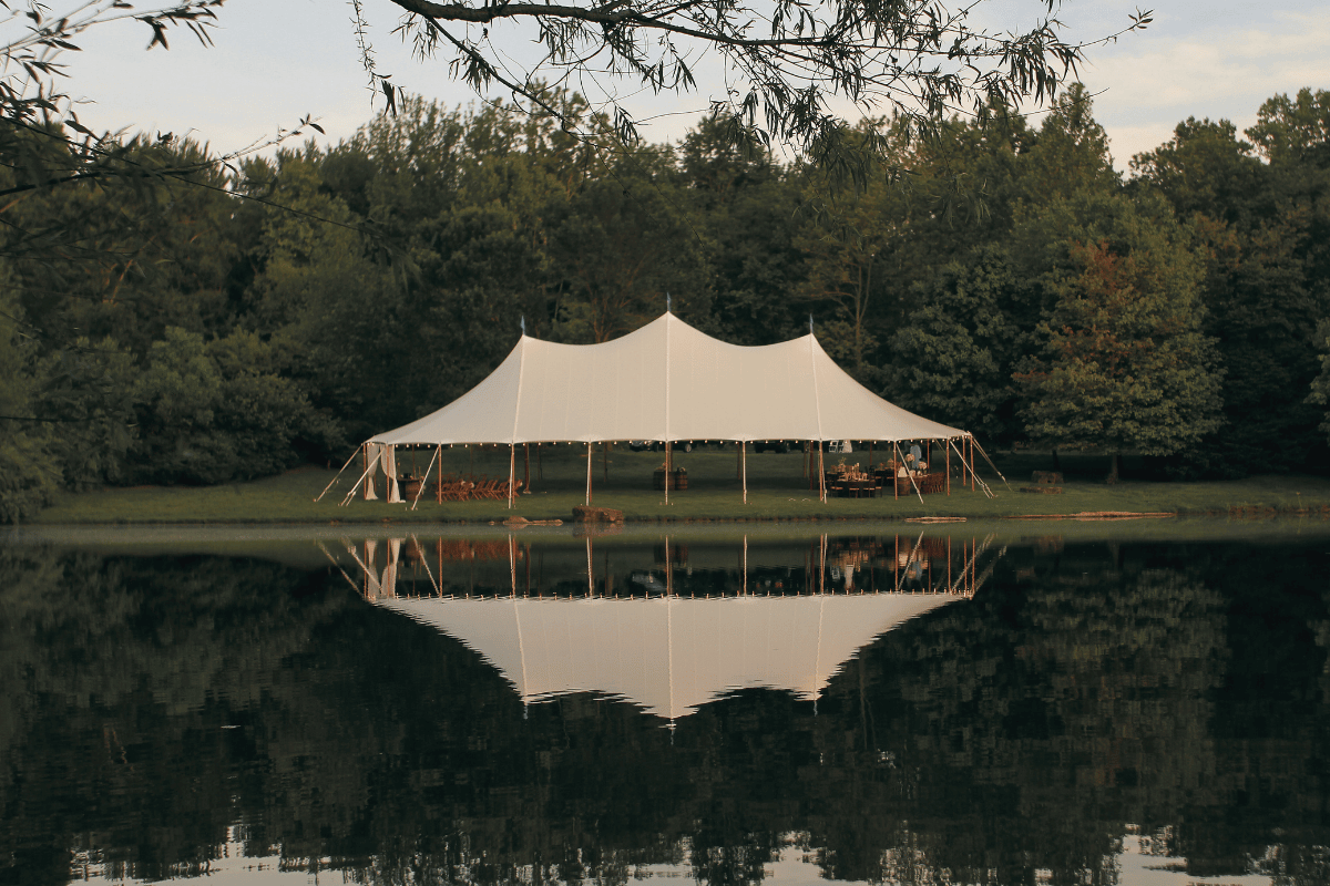 A Sailcloth Marquee sits on grass in front of a pond