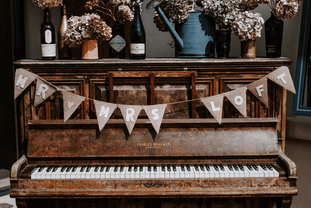 A brown piano is decorated for a wedding with a Mr & Mrs bunting