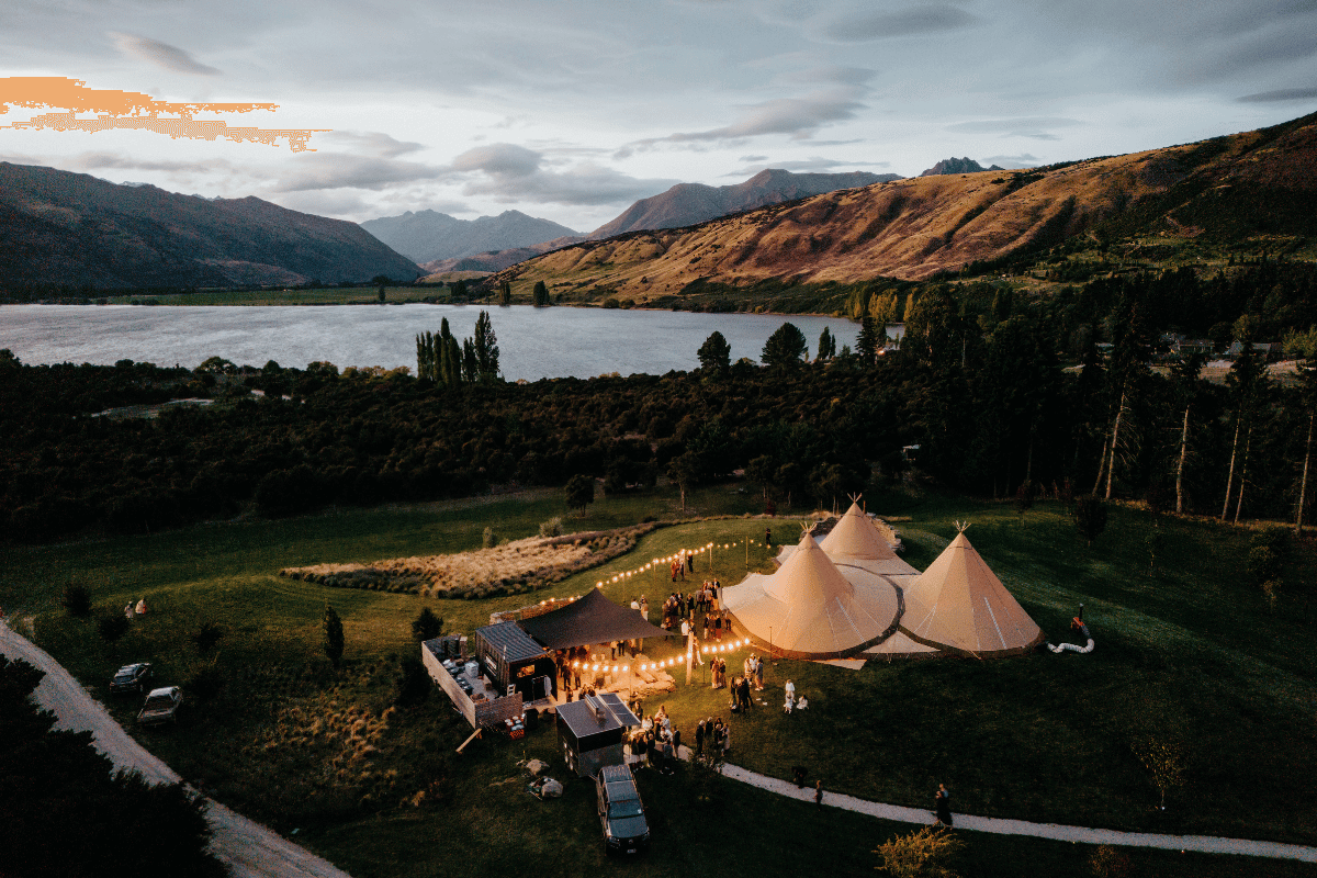 Drone image taken of three tipis overlooking a lake in New Zealand